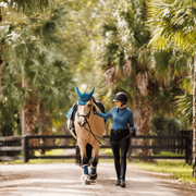 Woman wearing the Marina equestrian riding shirt. She is showing off the perforated arms and cuffs of the long sleeves and the wave like pattern of the mock neck.